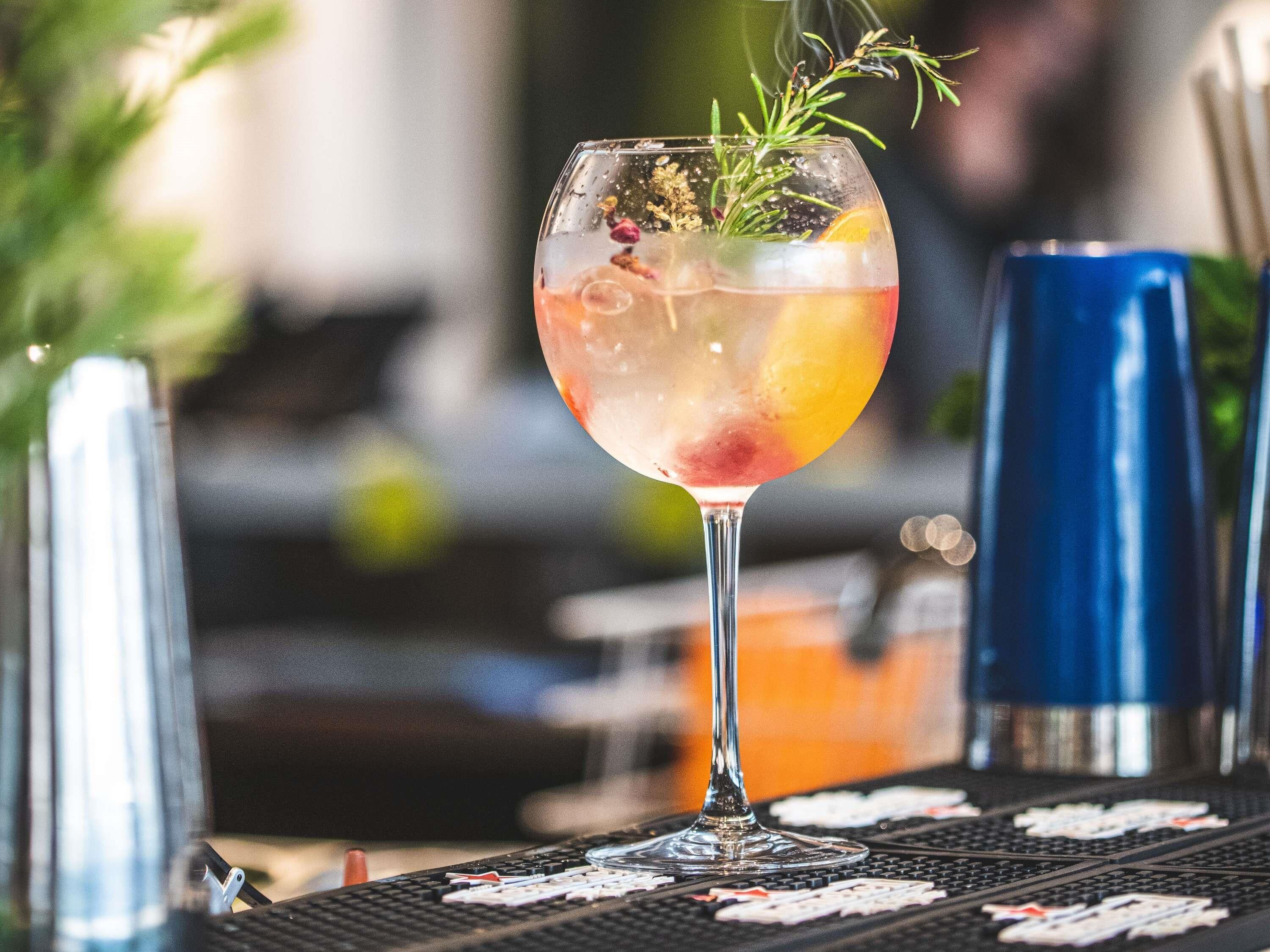 Een cocktailglas met garnering op een bar.