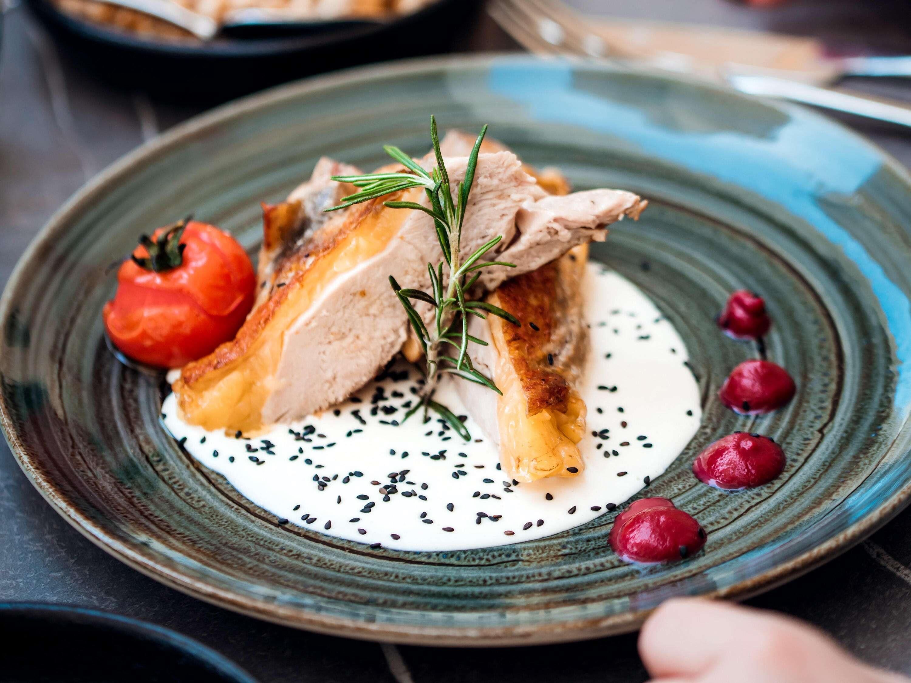 A plate with food, a sprig of rosemary, and black sesame seeds.