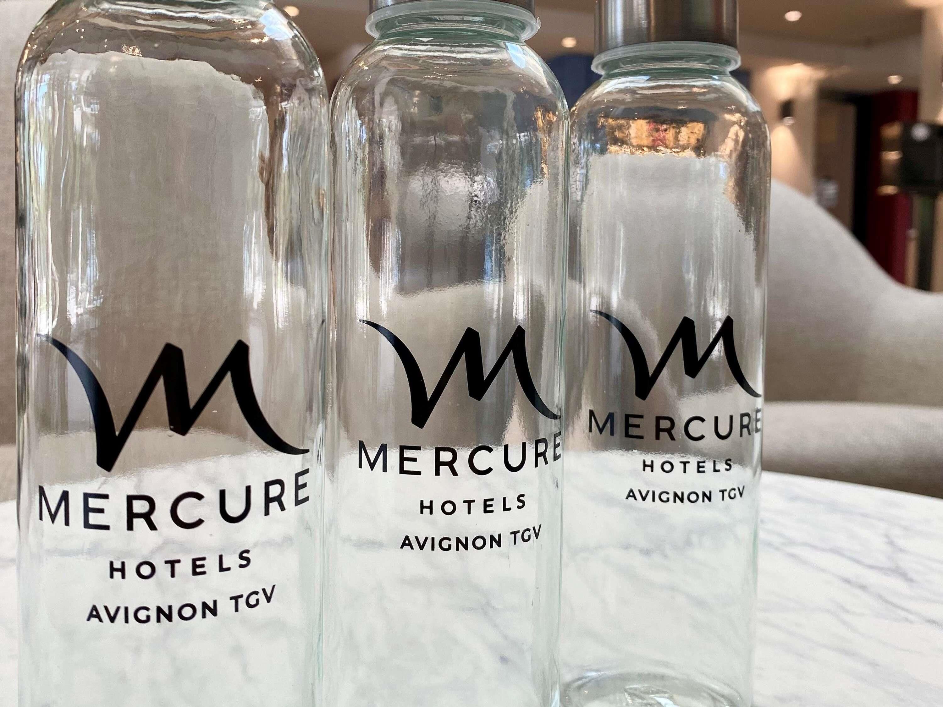 Drie glazen flessen met het label 'Mercure Hotels Avignon TGV' en een gestileerd 'M'-logo.
