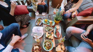 A group of people seated around a table with various dishes and drinks, indicating a social gathering or meal.