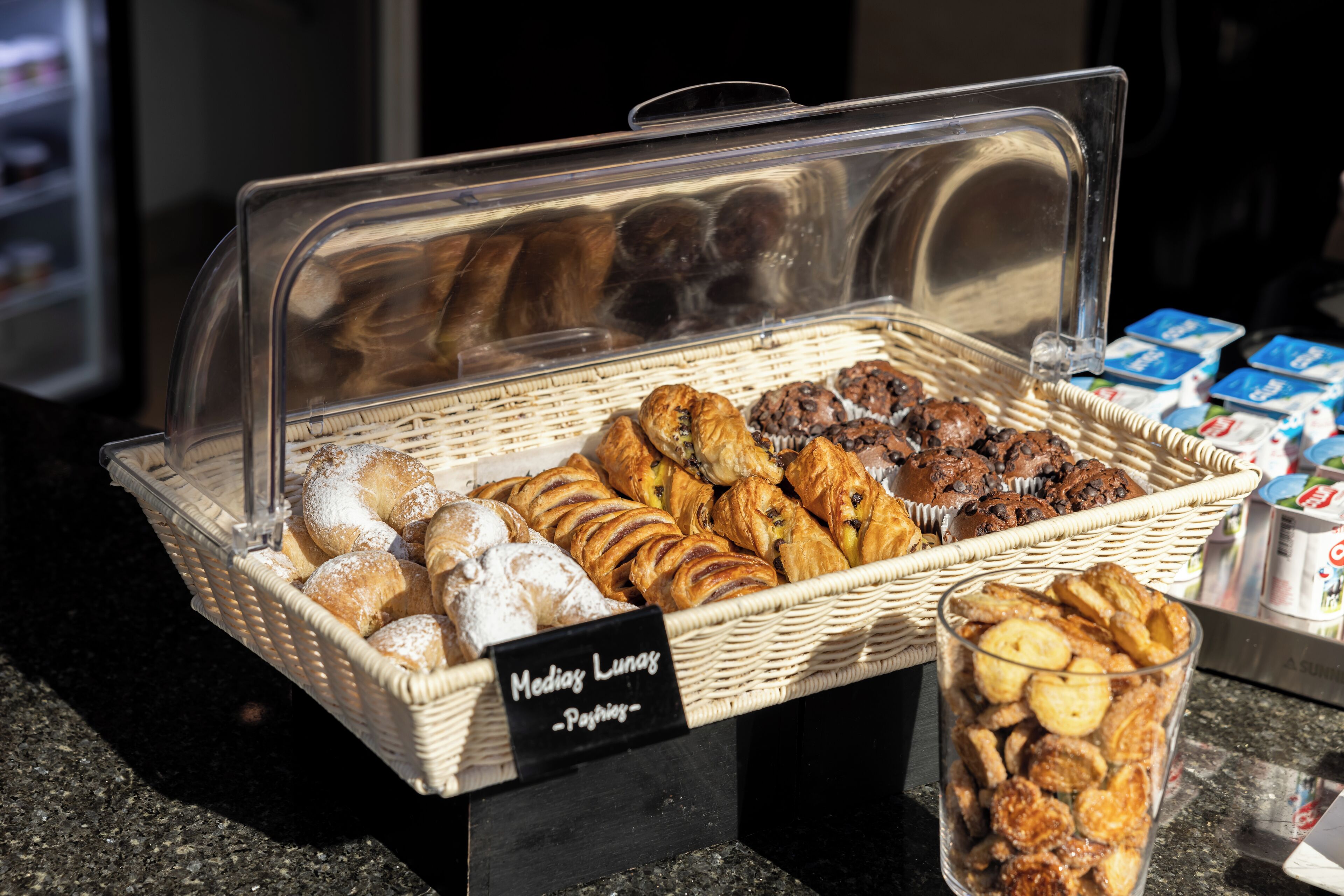 Una vitrina de pastelería con diversos pastelitos y un letrero que dice 'Media Luna Pastries'.