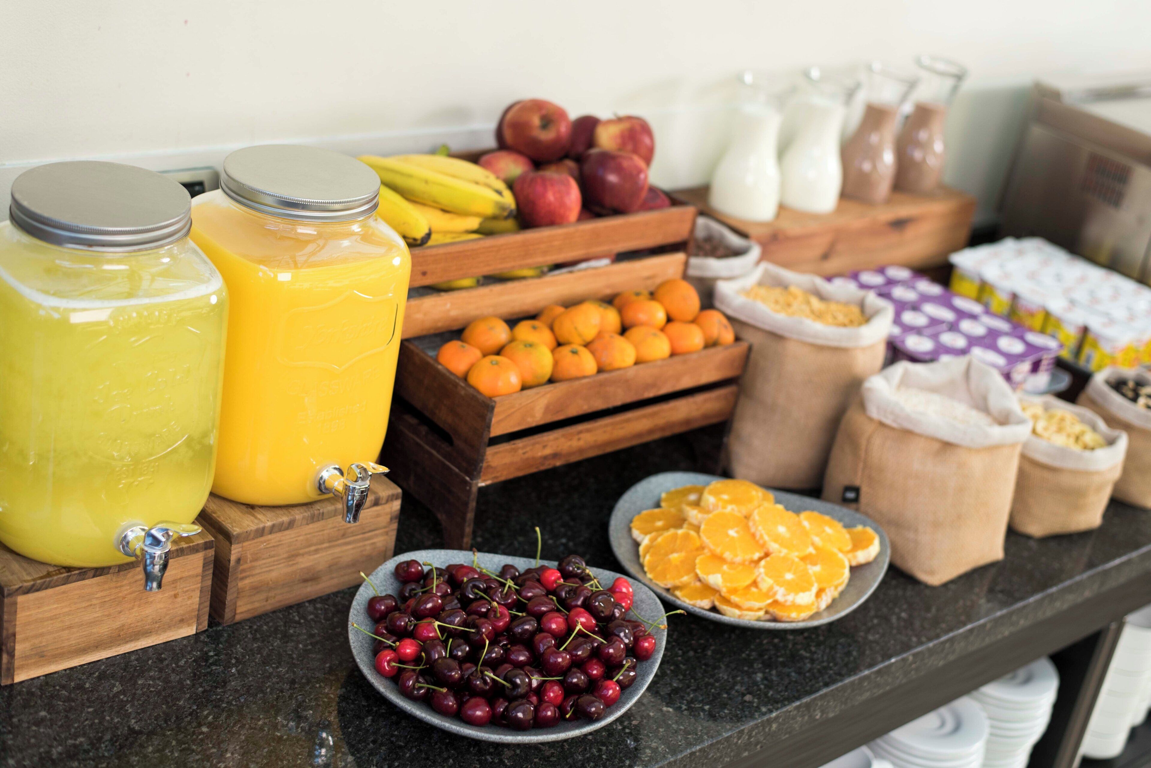 Un bufé de desayuno con diversas frutas, jugos y productos lácteos.