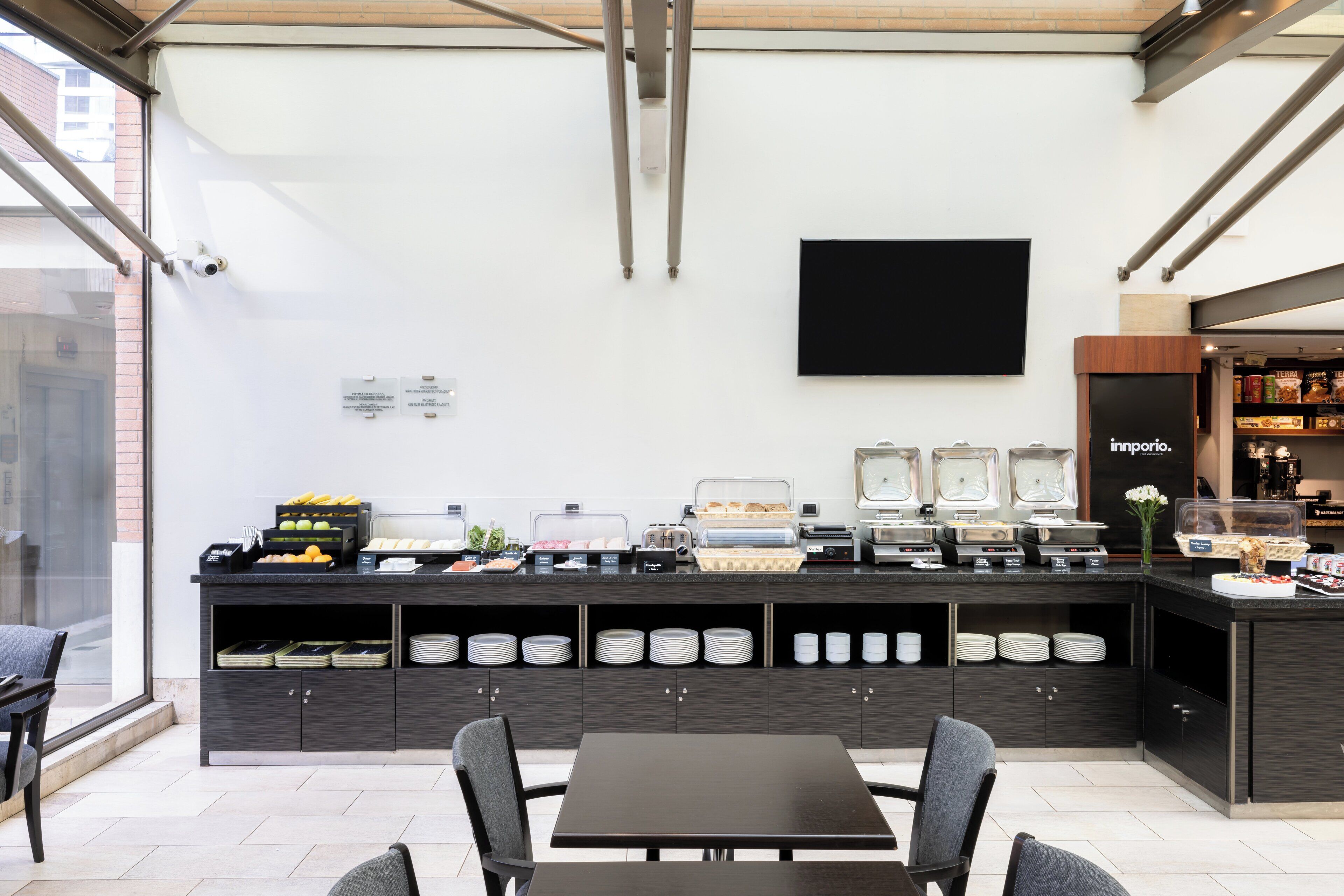 A modern kitchen with a breakfast bar, a flat-screen TV, and a coffee station.