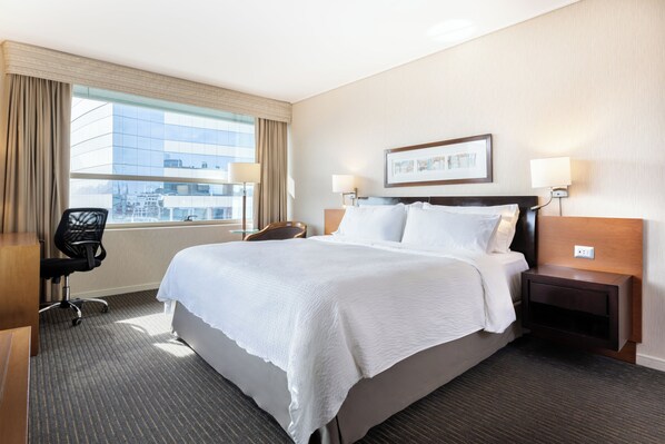 A hotel room with a large bed, a desk, a chair, and a window with a view of a building. - Holiday Inn Express Santiago Las Condes by IHG (Santiago)