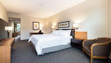 A hotel room with a large bed, bedside tables, a desk, and a chair.