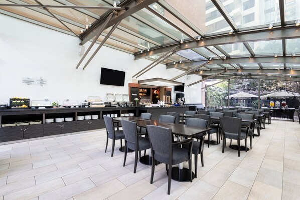 A spacious outdoor dining area with a glass roof, modern furniture, and a bar counter. - Holiday Inn Express Santiago Las Condes by IHG (Santiago)