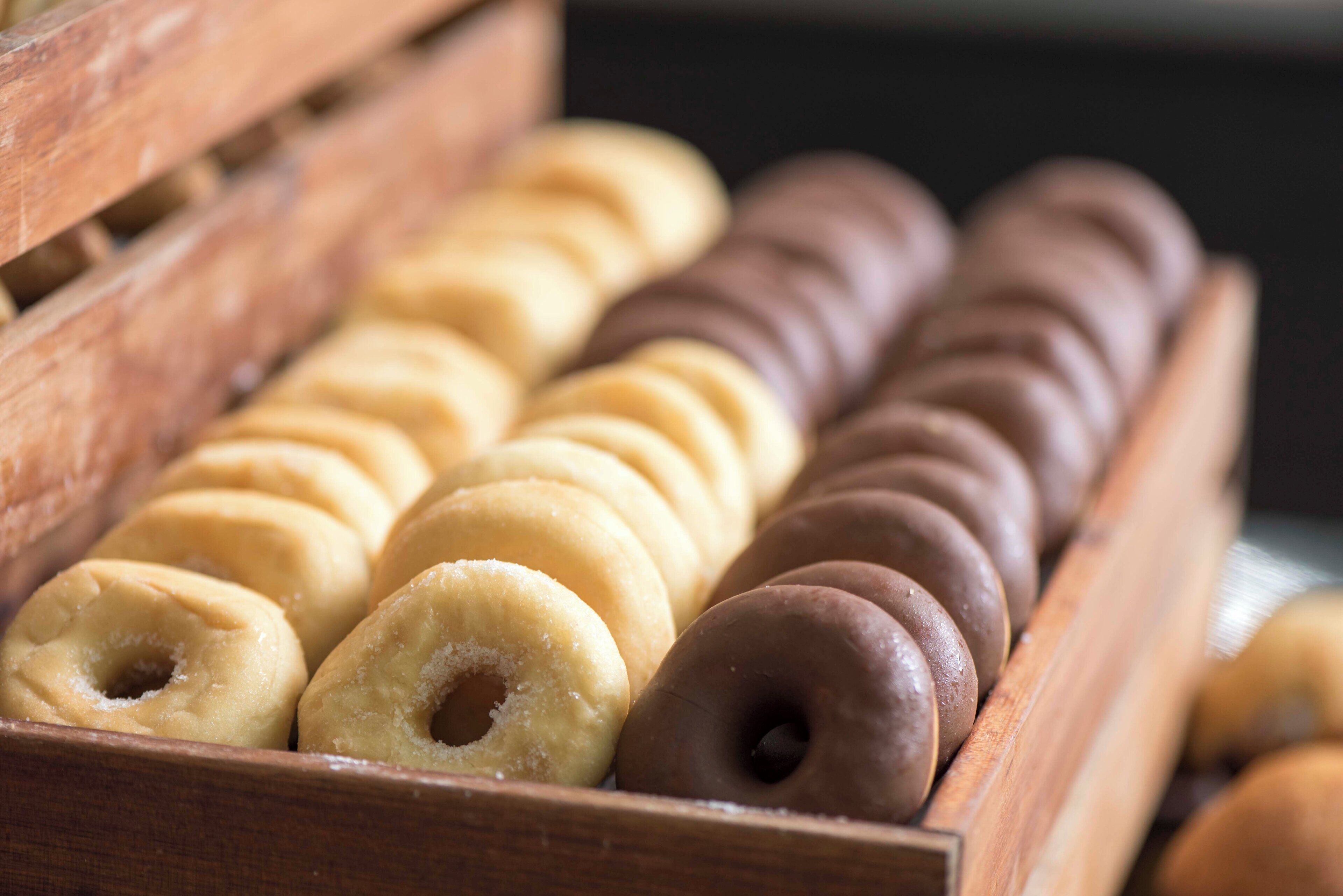 A wooden box containing various doughnuts.