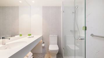 A modern bathroom with a large white sink, a toilet, and a glass-enclosed shower.