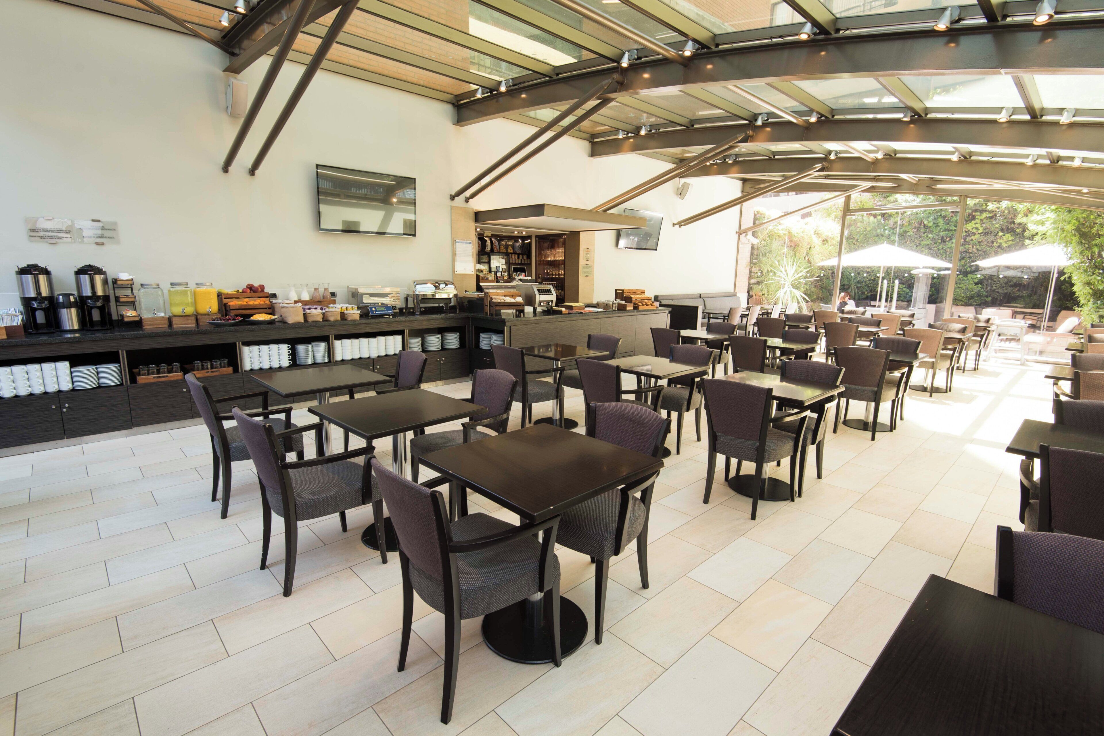 A cafe with outdoor seating, a bar area, and a breakfast buffet.