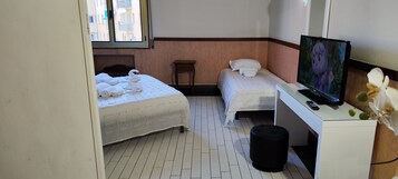 Een hotelkamer met twee bedden, een televisie, een bureau en een prullenbak.