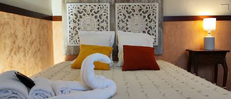 A hotel room with a bed, two pillows, a lamp, and a towel.