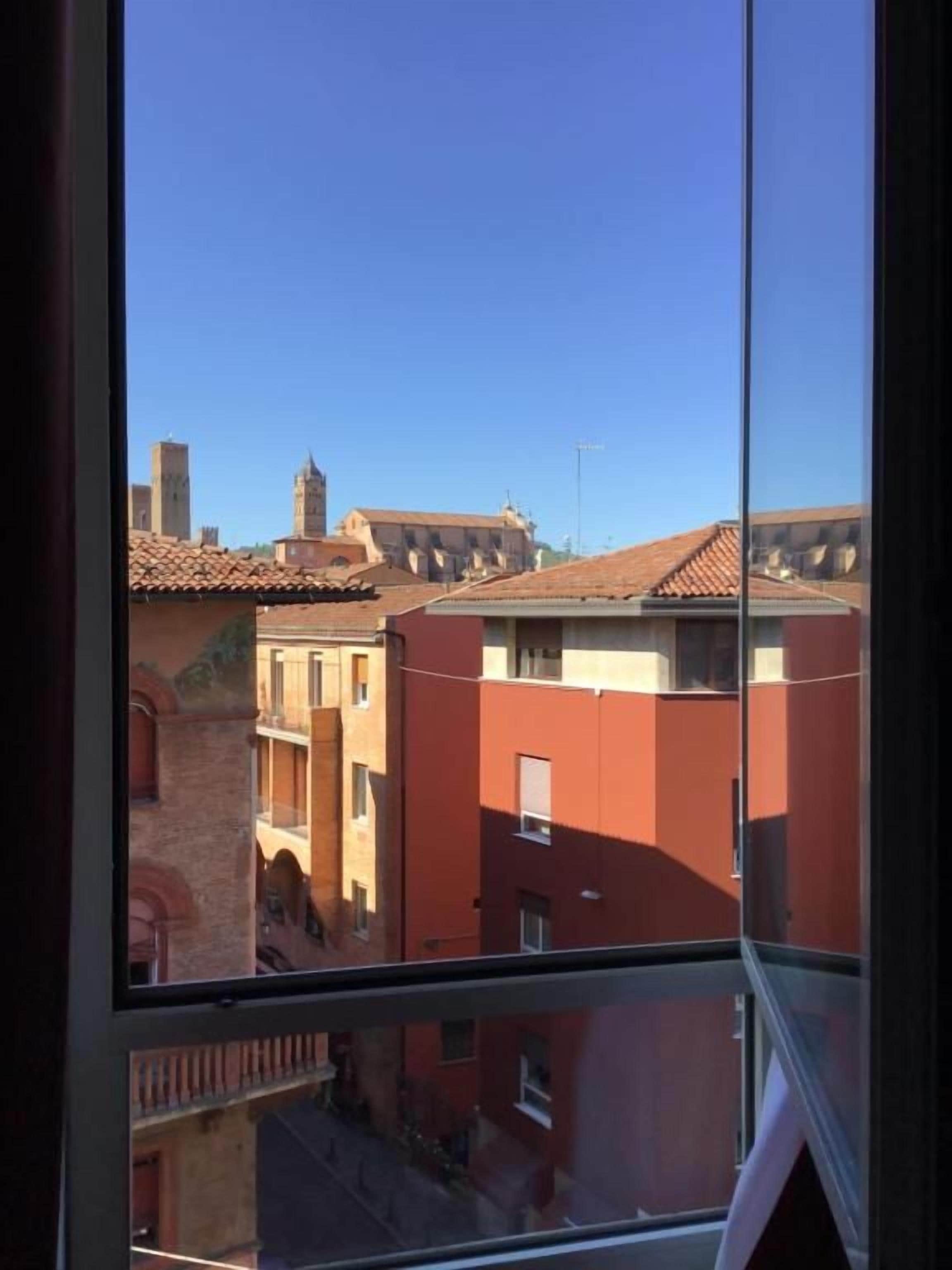 A view through a window of a building with multiple balconies and a clear sky.