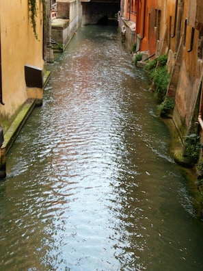 Un étroit canal bordé d’immeubles, avec un pont qui le surplombe.