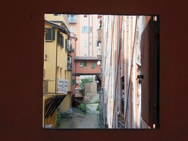 A narrow alleyway between buildings with a sign indicating a historical site.