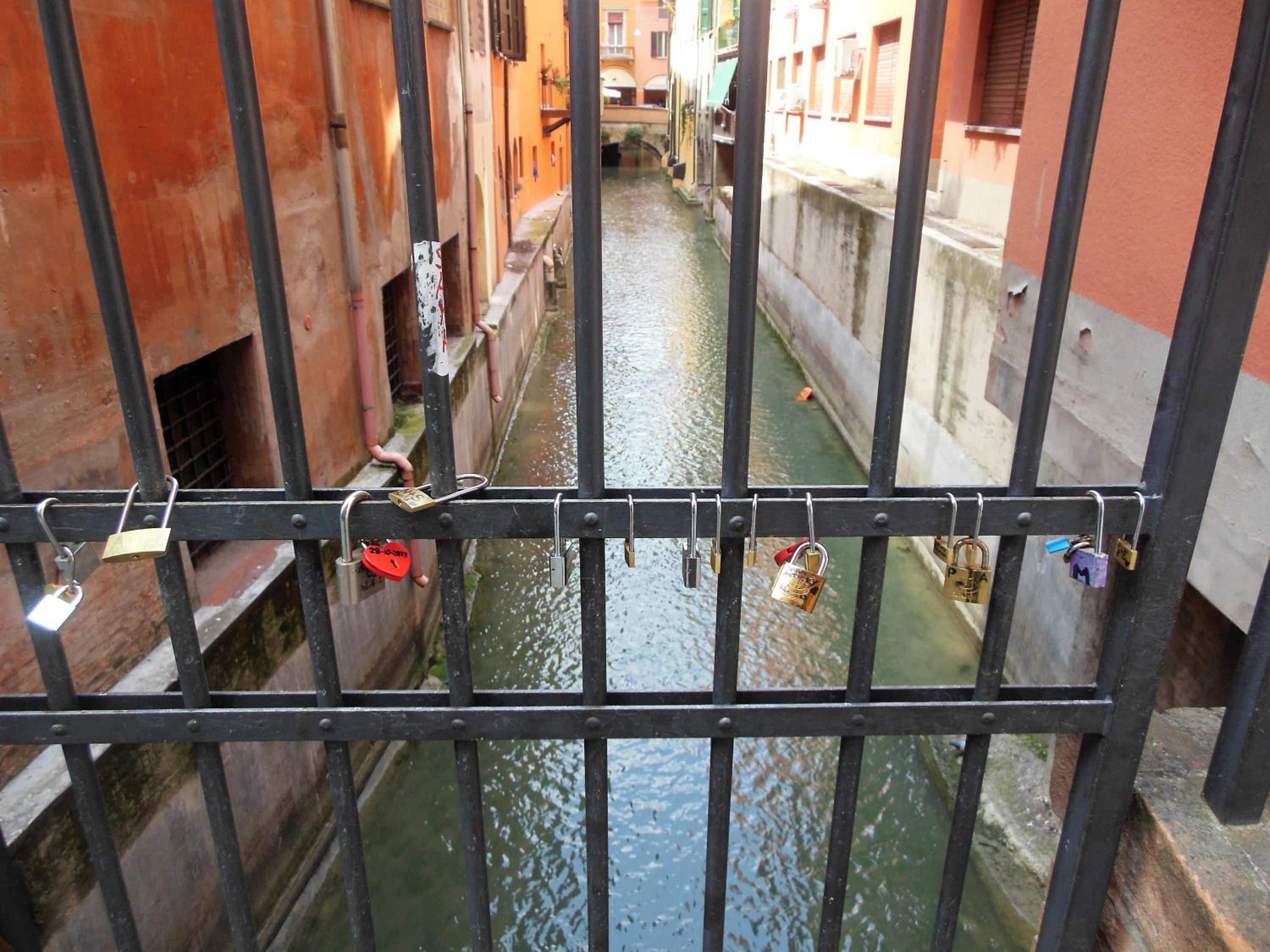 Un canal estrecho bordeado por edificios, con una reja metálica al frente.