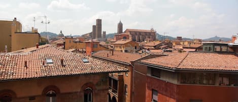 Un paysage urbain caractérisé par des toits traditionnels recouverts de tuiles rouges, des bâtiments historiques et un clocher d’église imposant.