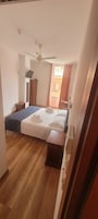 Een kamer met een bed, een plafondventilator en uitzicht op buiten.
