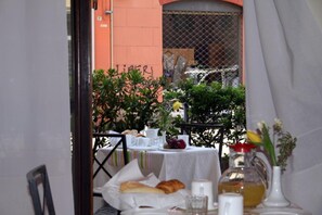 A table set for breakfast with a basket of bread, a glass of juice, and a vase with flowers. - Hotel San Giorgio (Bologna)