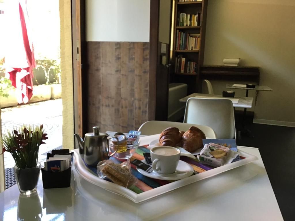 A breakfast tray with croissants, a cup of coffee, and a teapot on a table.
