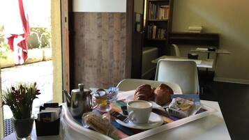 A breakfast tray with croissants, a cup of coffee, and a teapot on a table.