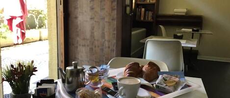Un plateau de petit-déjeuner avec des croissants, une tasse de café et une théière, posé sur une table.