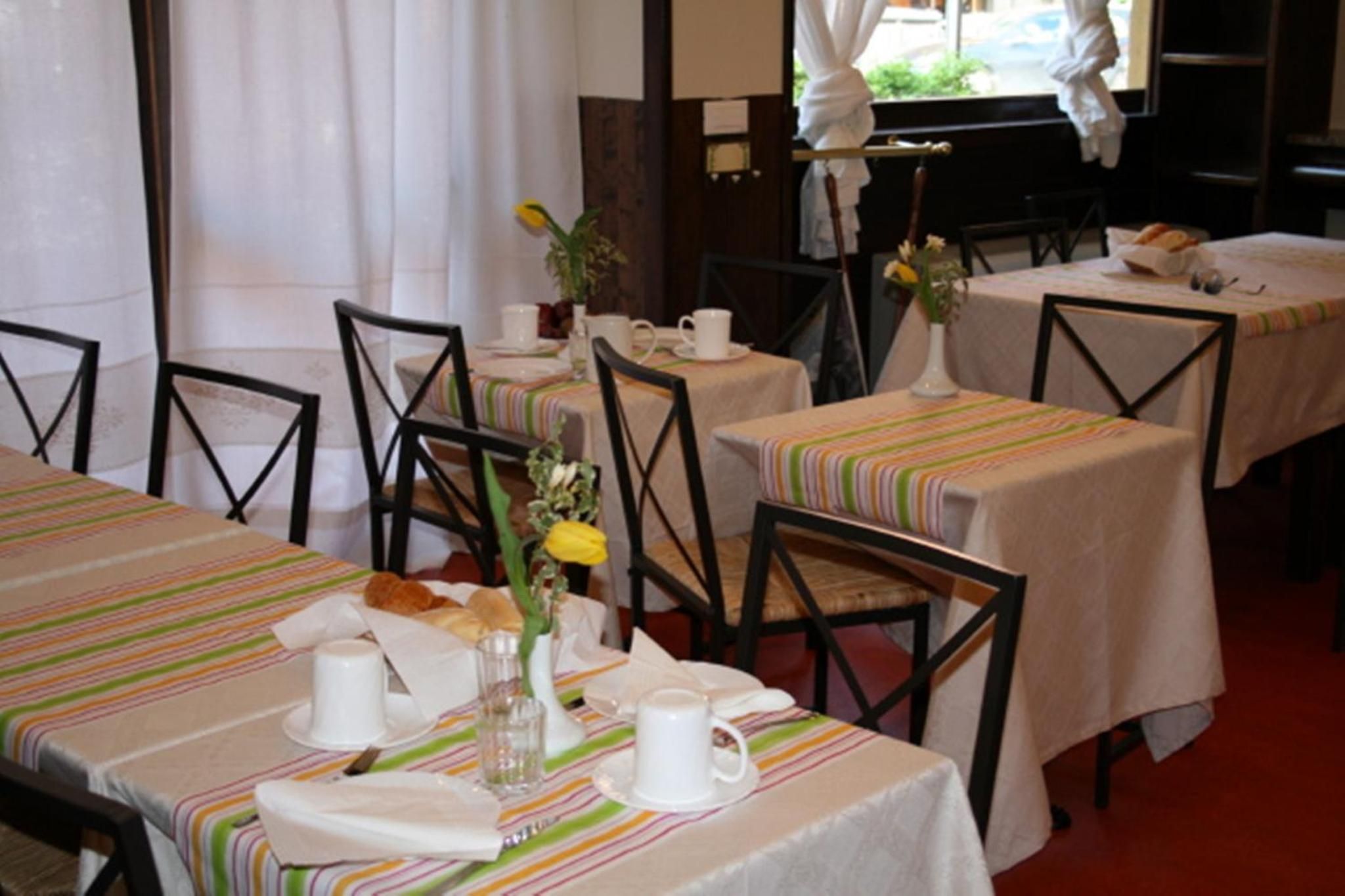 A dining area with tables set for breakfast, featuring striped tablecloths and chairs.