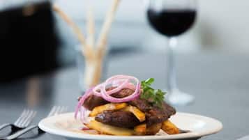 A plate with a sandwich, fries, and a glass of red wine on a table.