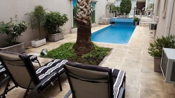 Relax by the inviting pool surrounded by a patio area with lounge chairs and lush greenery.