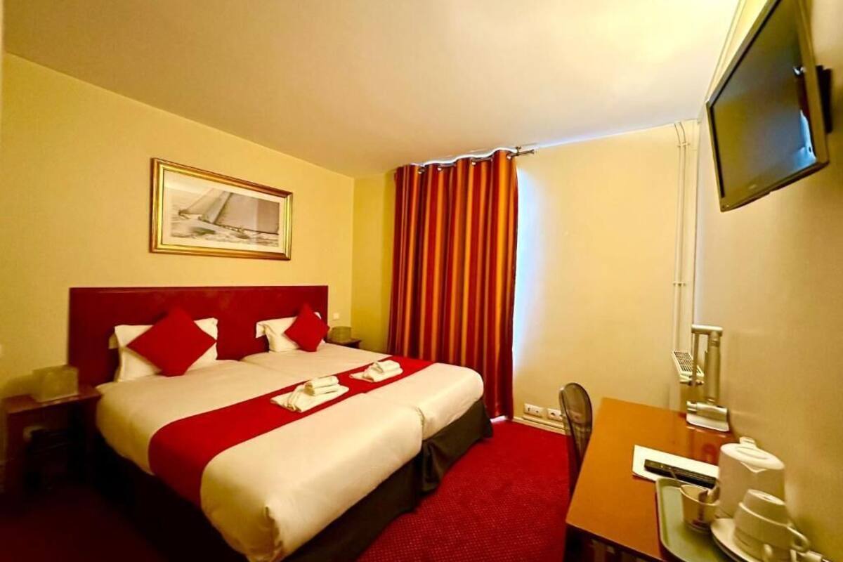 Een hotelkamer met een bed, een bureau, een stoel, een televisietoestel en een raam met gordijnen.