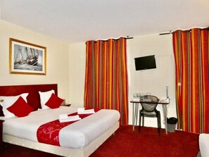 A hotel room with a bed, a desk, a chair, a TV, and curtains. - Hôtel Bellevue Paris Montmartre (Paris)