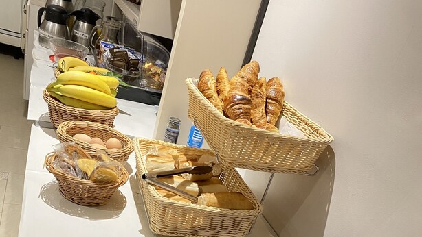 Een buffet met broodbakken, bananen en croissants.