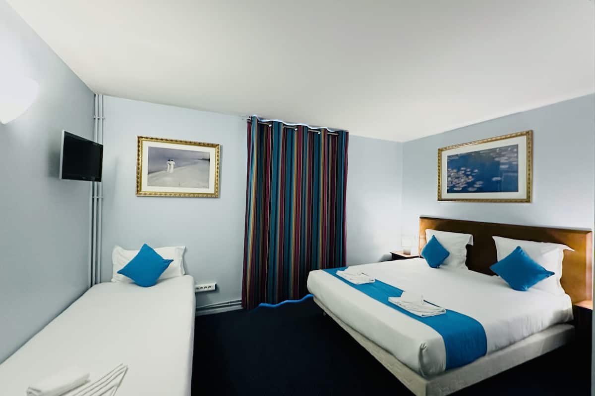 Een hotelkamer met twee bedden, een televisie en twee ingelijste foto's aan de muur.