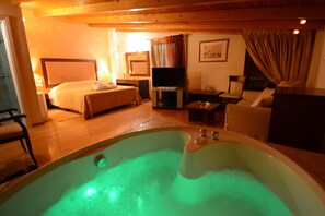 A room with a large bathtub, a bed, a television, and a seating area. - Hotel Chris (Kifisia)