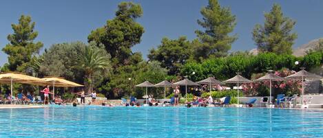 Una piscina al aire libre, sombrillas, sillones reclinables de piscina