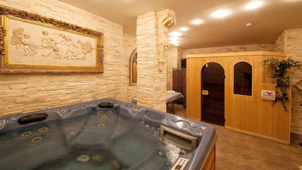 A spa area with a hot tub, stone walls, and a wooden door. - Grand Hotel London (Varna)