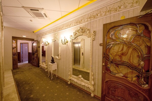 A hallway with ornate mirrors, a wooden door with a stained glass design, and a carpeted floor. - Grand Hotel London (Varna)