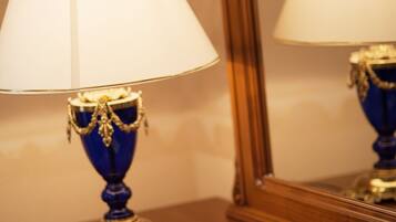 A wooden nightstand with a blue lamp, a mirror, and a notepad with a pen.