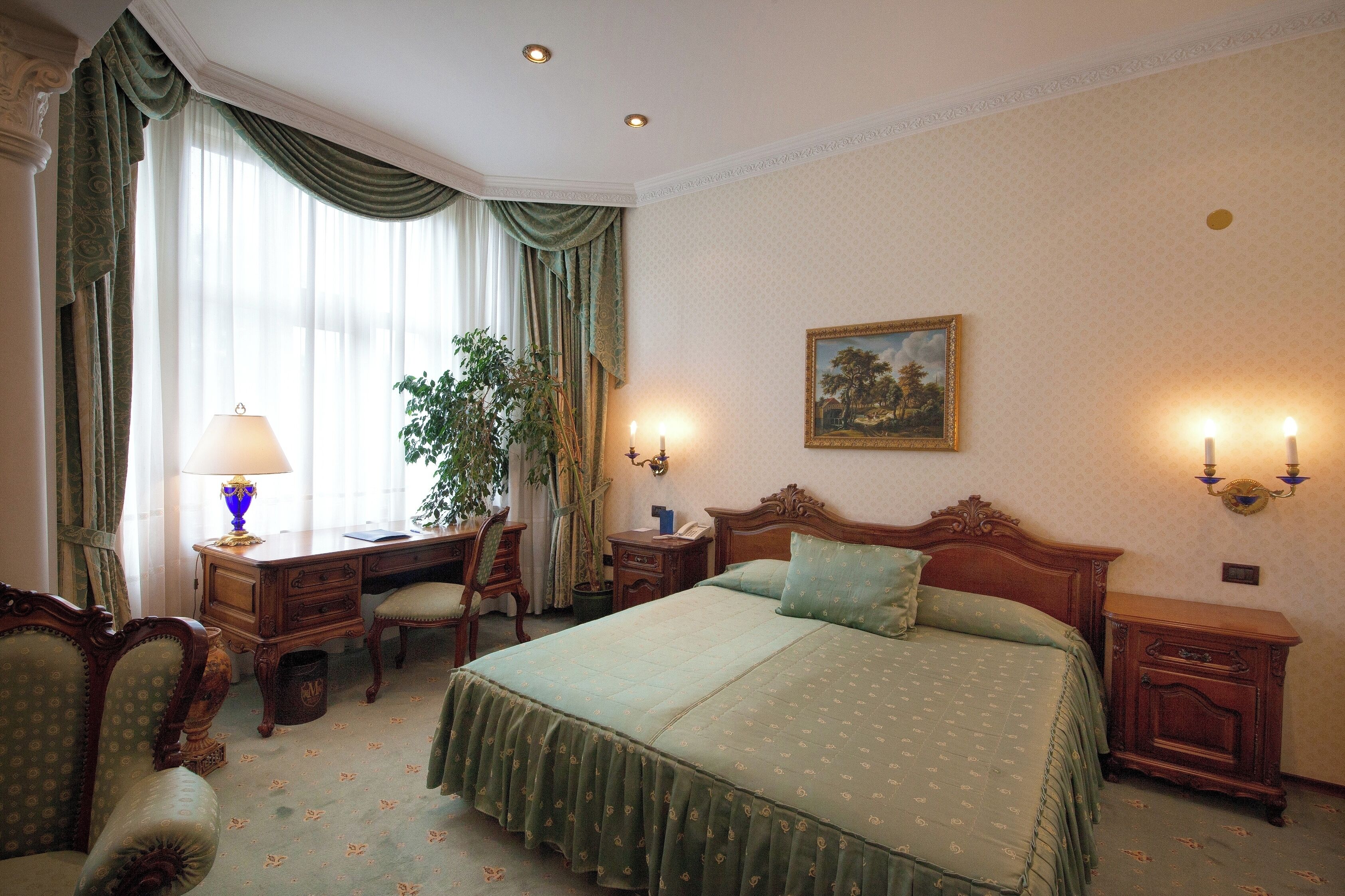 A traditional bedroom with a large bed, a desk, and a chair.