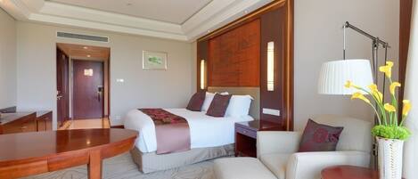 A hotel room with a bed, a sofa, a table, and a lamp.