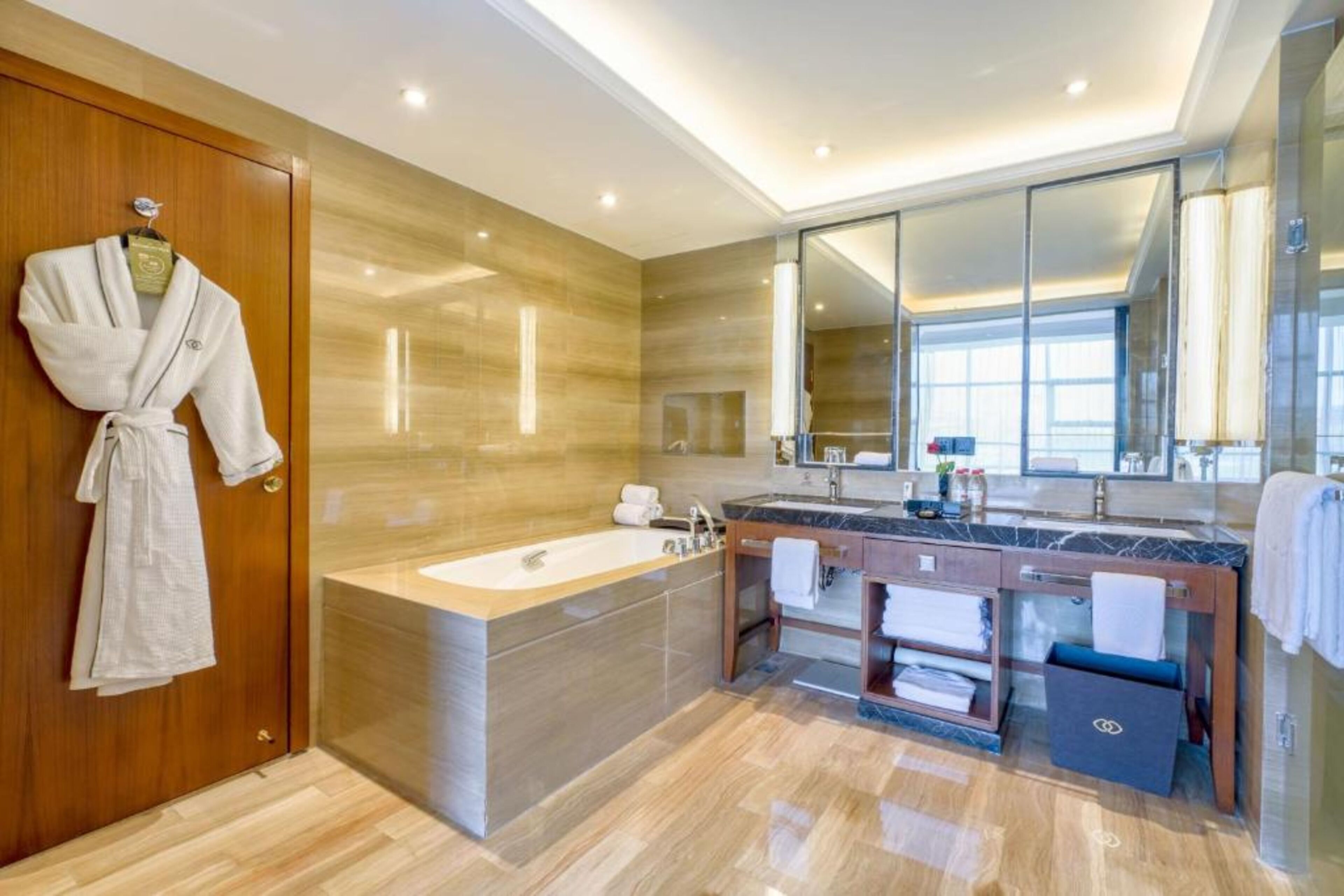 Un bagno moderno con una vasca da bagno grande, un mobile lavabo con specchio e un accappatoio appeso a una porta di legno.