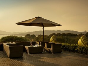 A deck with wicker furniture, a table with a teapot, and a large umbrella. - Sofitel Hangzhou Westlake (Hangzhou)