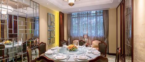Uma sala de jantar formal com uma mesa redonda, cadeiras e um lustre.
