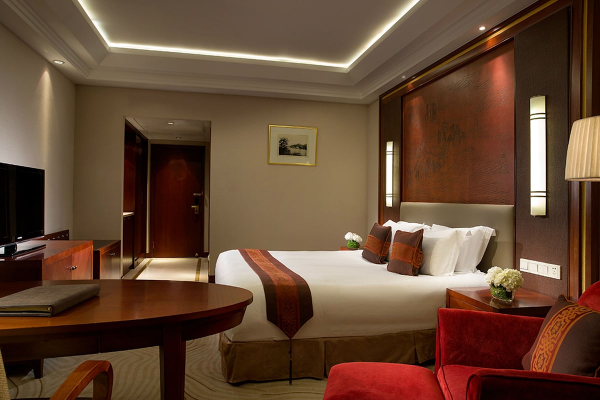 Een hotelkamer met een groot bed, een bureau, een stoel en een televisie.