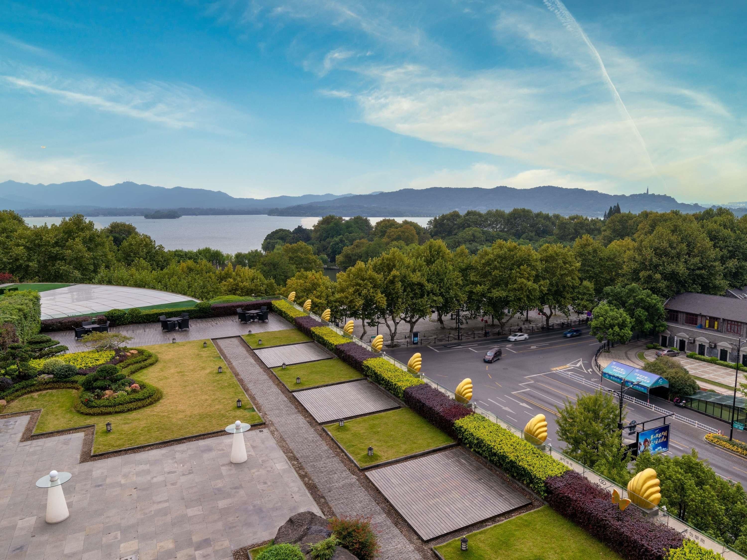 A landscaped outdoor area with seating, a view of a lake, and a road with vehicles.