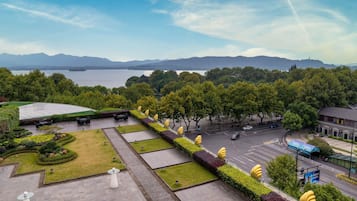 A landscaped outdoor area with seating, a view of a lake, and a road with vehicles.