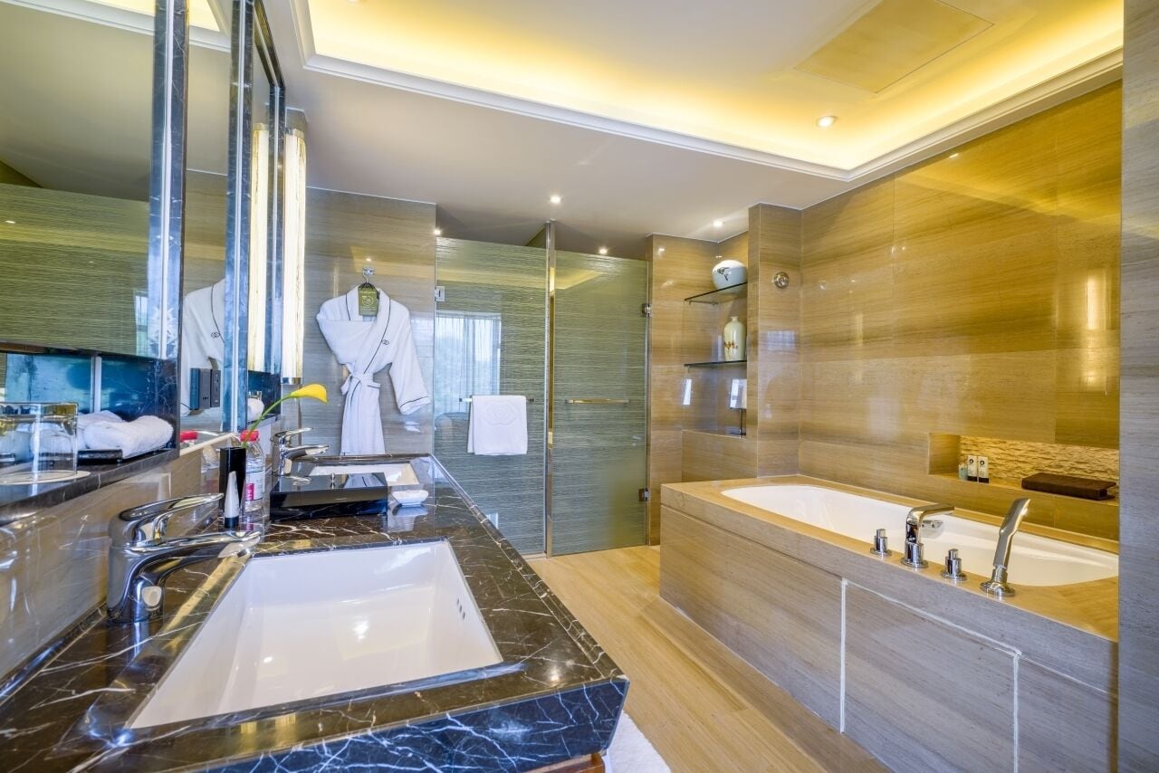 Un baño moderno con un espejo grande, dos lavamanos, una bañera y un box de ducha de vidrio.