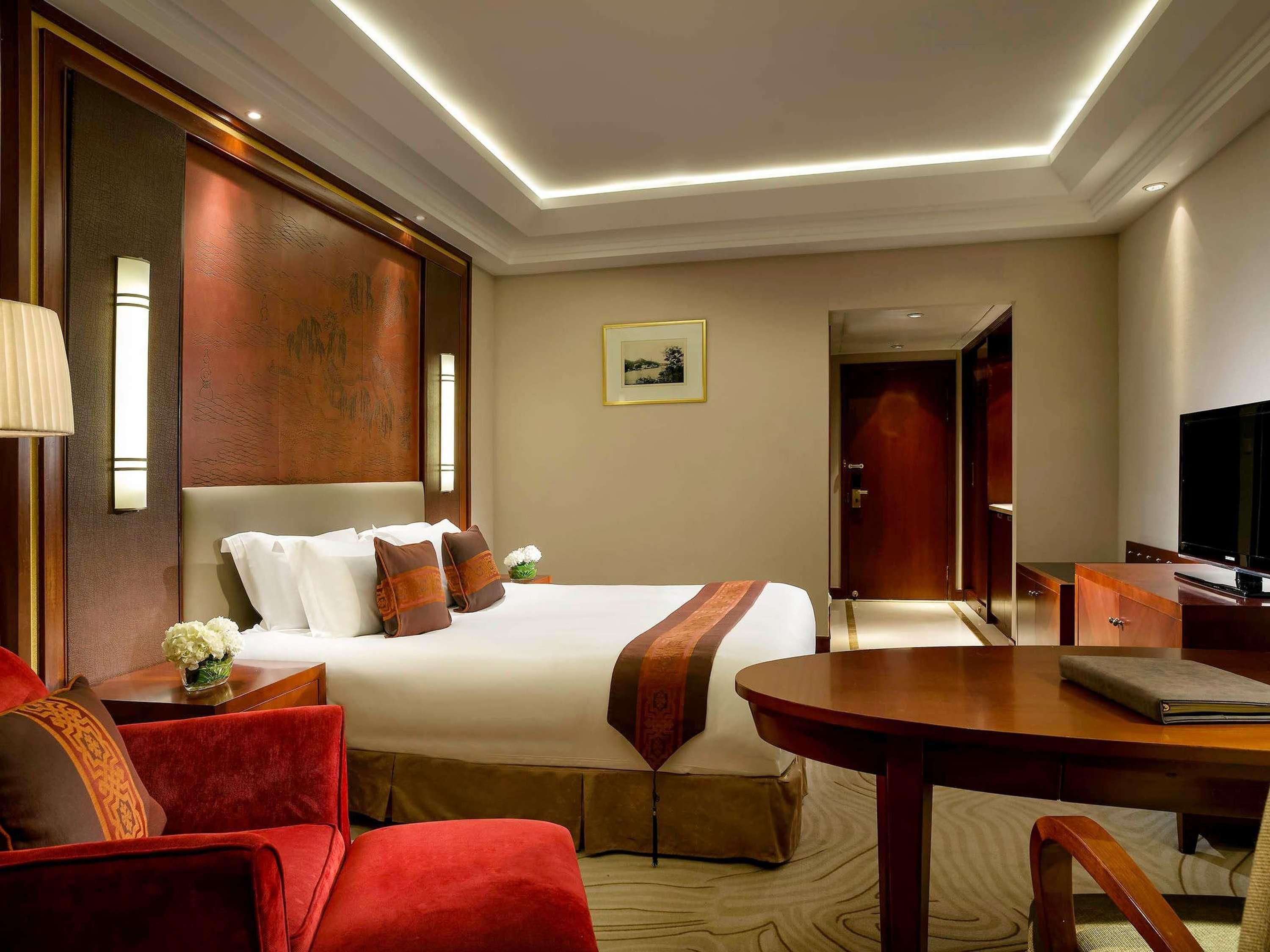 Ein Hotelzimmer mit Bett, Schreibtisch, Stuhl, Fernseher und einer Tür.