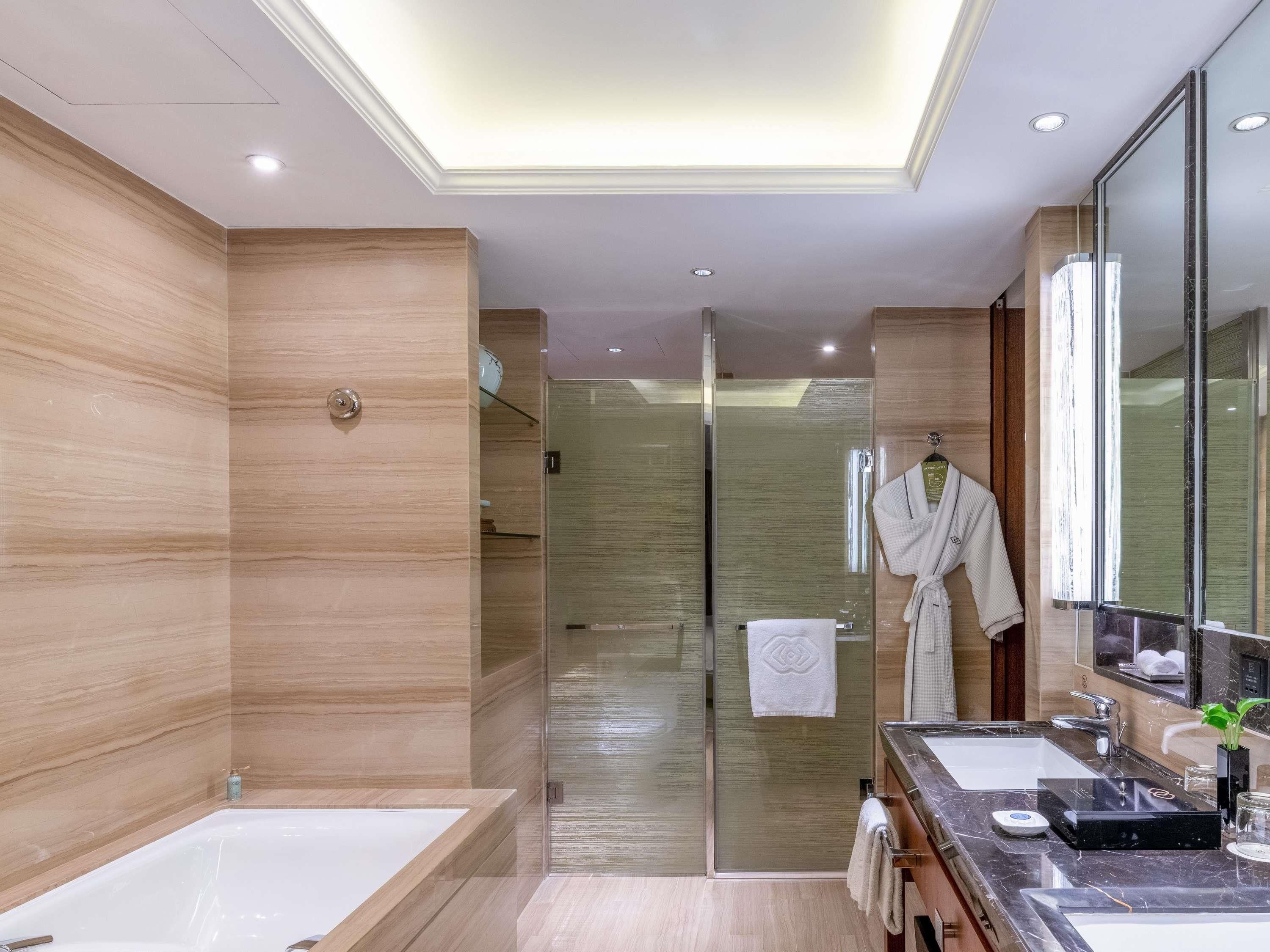 A modern bathroom with a large bathtub, a glass-enclosed shower, and a vanity with a mirror.
