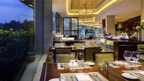 Un restaurante bien iluminado con mesas dispuestas para comer, una zona de bar y vistas al exterior.
