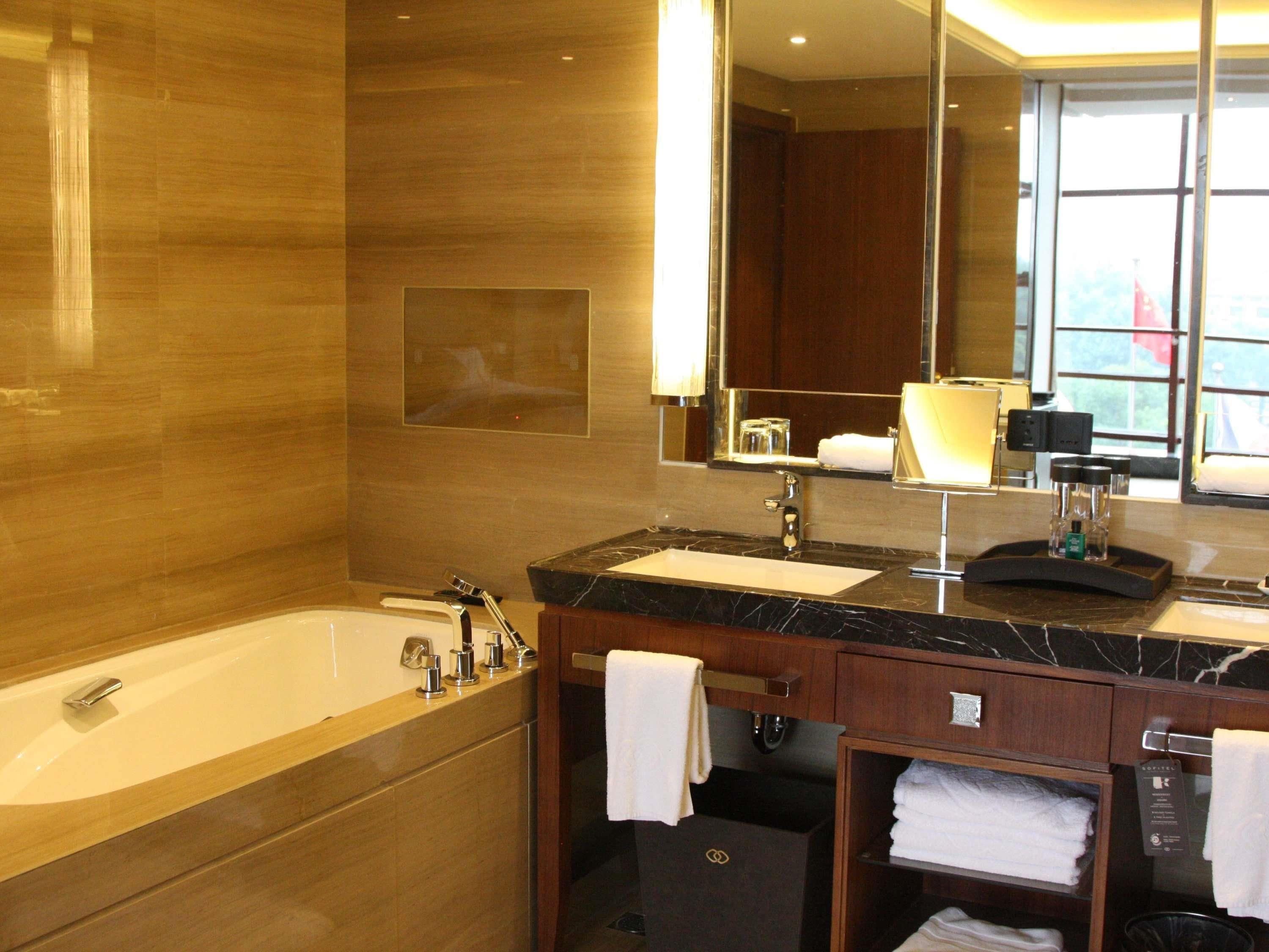 A modern bathroom with a bathtub, a sink, a mirror, and a vanity with a towel rack.
